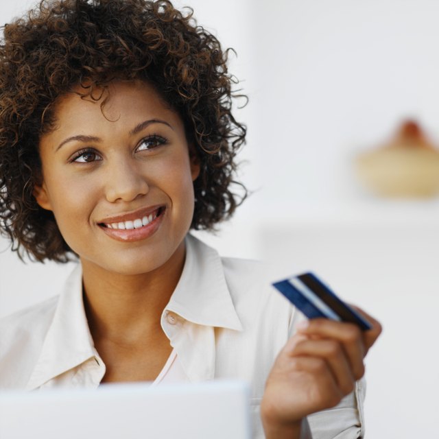 Portrait of a woman holding a credit card and using a laptop