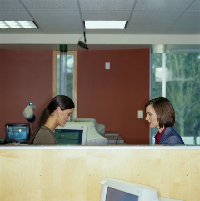 Bank teller assisting female customer, side view