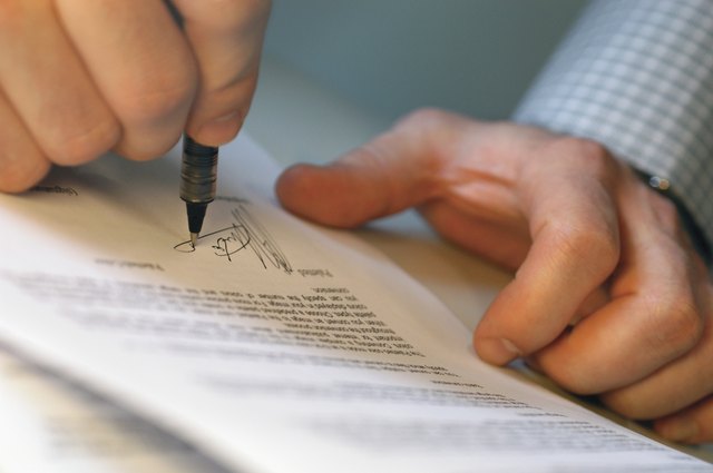 Close-up of a mans hands signing on a document