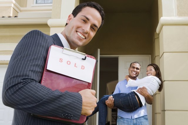 Hispanic real estate agent and African couple in front of house