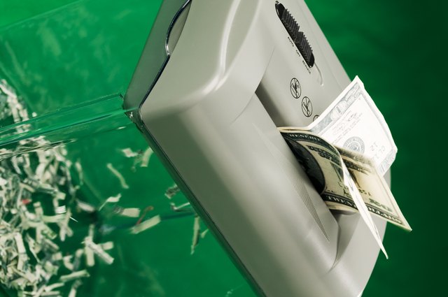 Twenty dollar bills going through a paper shredder