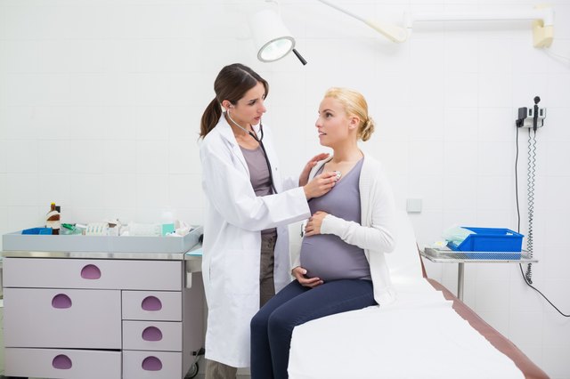Female doctor auscultating a pregnant woman on an examination table