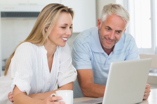 Happy couple using laptop together at the counter