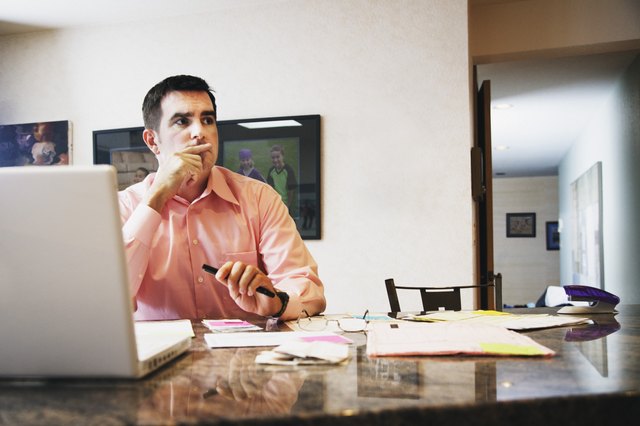 Pensive man sitting in front of laptop computer