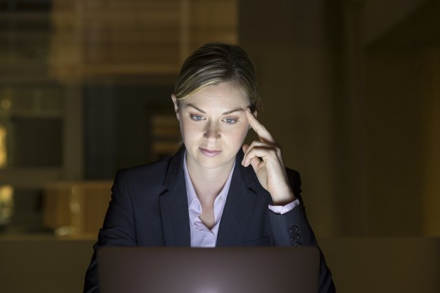 Businesswoman working late in her office on laptop, night light
