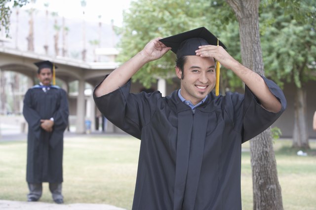 Young graduate student holding mortar board, portrait