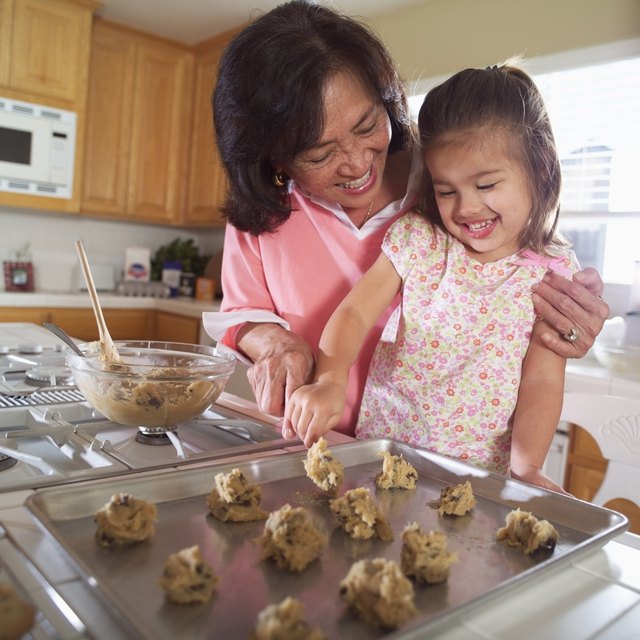 Grandmother helping granddaughter bake cookies