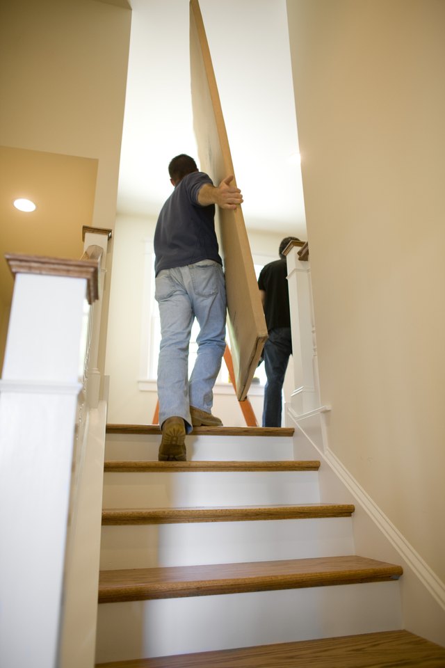 Contractors carrying boxes upstairs in house