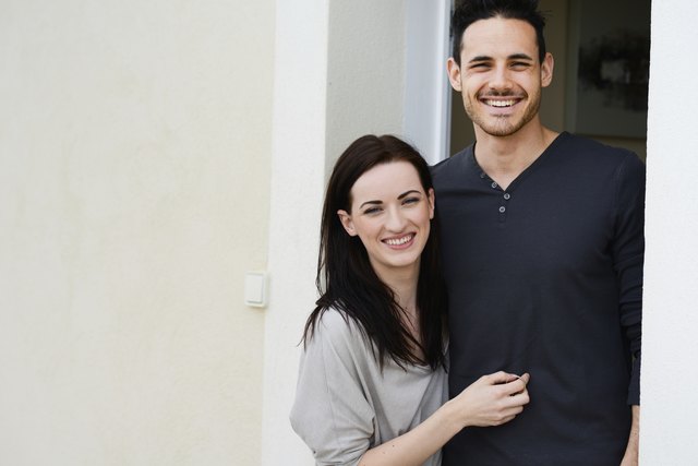 happy young couple welcome in new house at door entrance