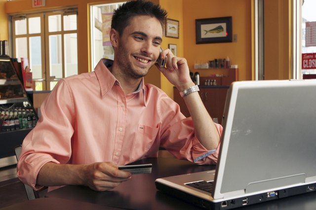 Young man talking on a mobile phone holding a credit card