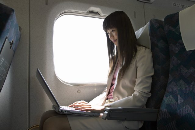 Businesswoman Sitting in a Passenger Train and Using a Laptop
