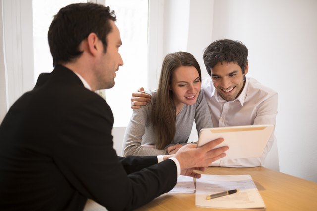 Young Couple meeting real-estate agent to buy property, presentation tablet
