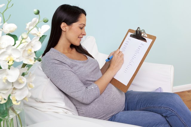 Pregnant woman sitting in a chair writing baby names