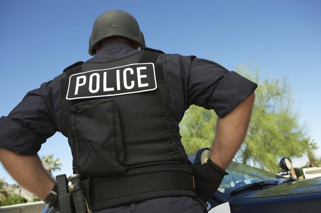 Police officer in bulletproof vest outdoors, back view