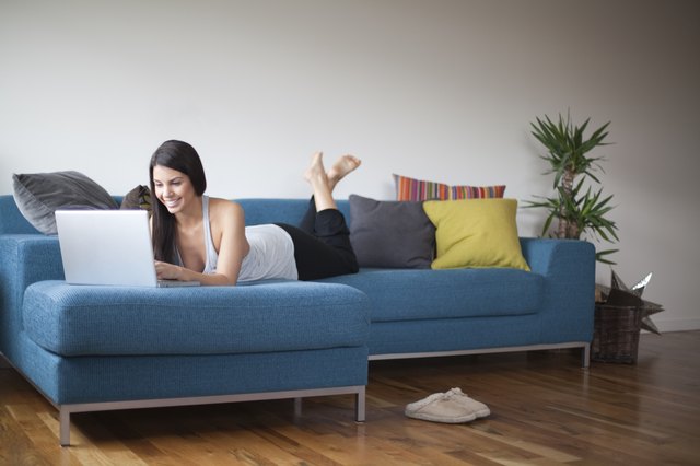 Young woman reclining on couch with laptop computer