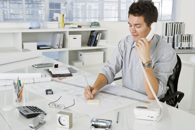 Architect on phone while writing on notepad