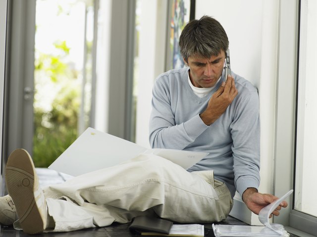 Man sitting in hallway, using mobile phone