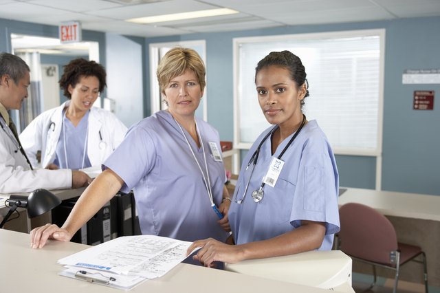 Doctors and nurse at reception desk, making notes in schedule book
