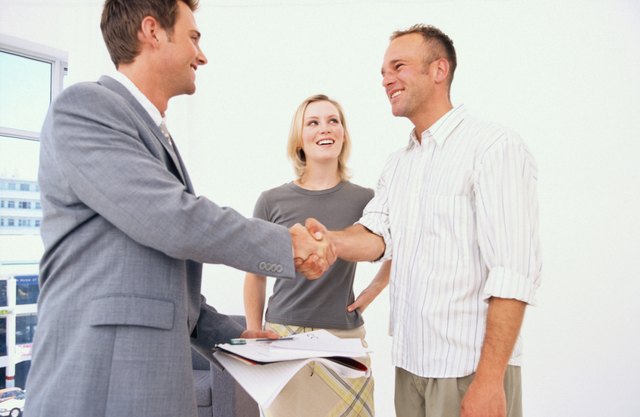 Real estate agent shaking hands with couple