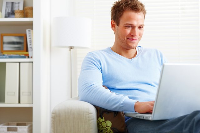 Close-up of young man using laptop and smiling