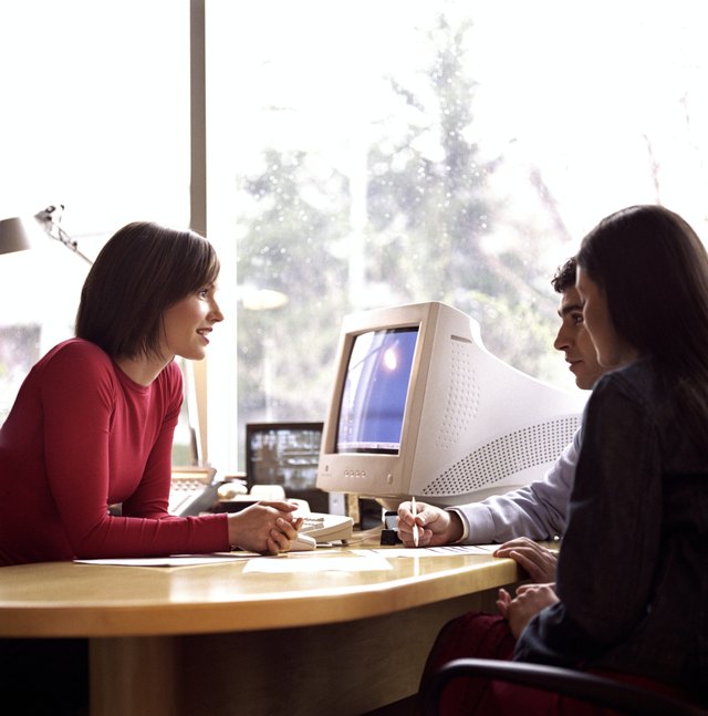 Young couple meeting with woman at desk, side view